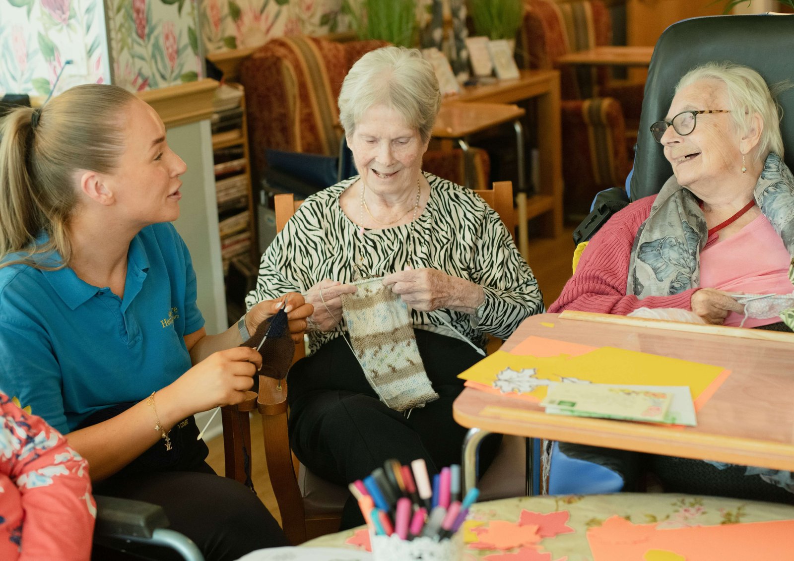 Friendly caregiver sharing a warm drink with an elderly person in a cosy living room.